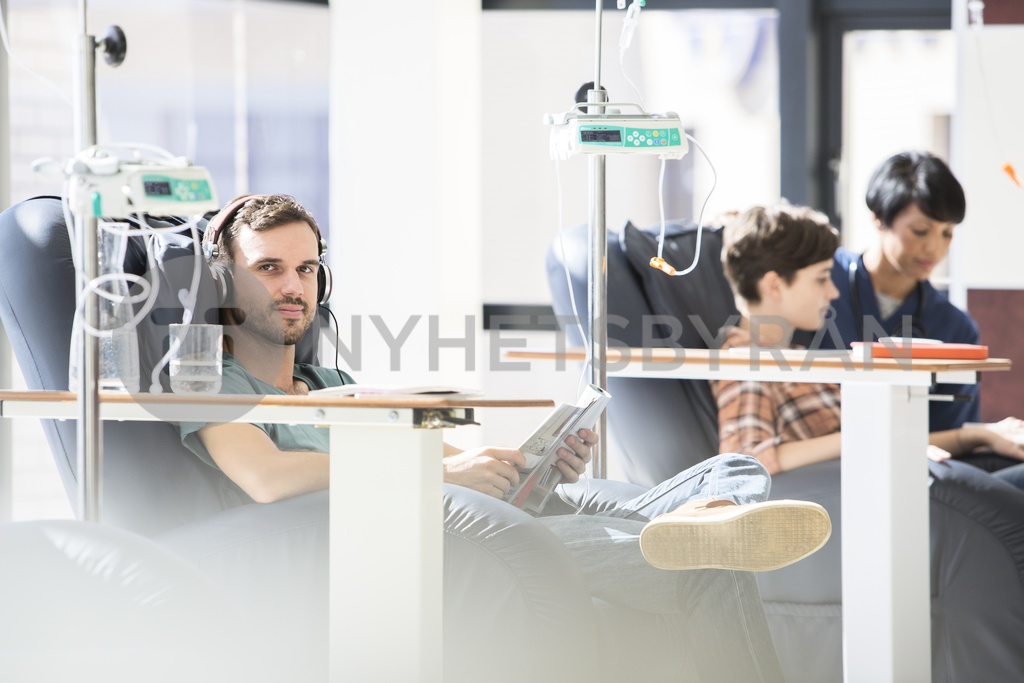 Patients in armchairs receiving medical treatment in hospital ward
