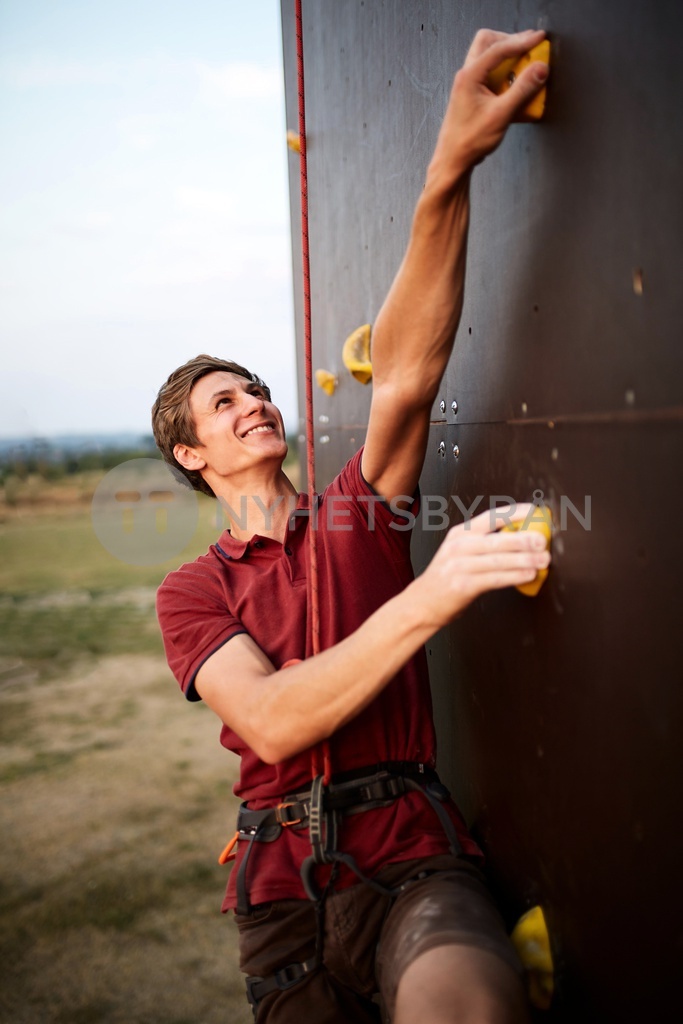 Sporty man practicing rock climbing in gym on artificial rock training ...